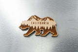 The California Bear Wood Magnet is crafted from sustainably harvested wood and laser engraved with CALIFORNIA, mountain, and pine tree designs. This unique cutout sits elegantly on any metallic surface.