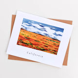 The California Poppy Field Note Card shows Karin Shelton's colorful painting of orange poppy fields, green patches, and a blue sky. "California" is printed below—ideal as a custom gift card.