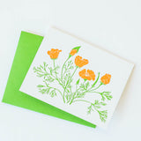 The California Poppy Letterpress Greeting Card features a white card with orange poppies and green stems, paired with a bright green envelope, shown on a white background.