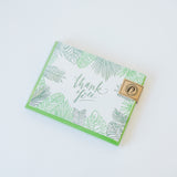 The Green Leaf Thank You Cards feature letterpressed green leaf illustrations and "thank you" in cursive, packaged with a brown paper label in the top right corner and displayed on a white background.