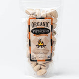 A 3 oz resealable bag of Hickory Smoke Santa Barbara Organic Pistachios features sea salt and bold hickory flavor in every bite. The package includes a campfire graphic, highlighting these Cuyama Valley organic nuts.