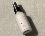 A white bottle of Lavande Lavender Lotion - Travel Size with a pump sits on a textured gray surface.