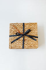 Light Afternoon Treats, a square woven basket tied with a black ribbon and adorned with dried flowers, ideal for holding handcrafted chocolate truffles, is displayed against a white background.