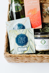 The Light Afternoon Treats gift basket includes Perrier, gluten-free California gummy bears, Steep Echo Bloom tea, and Santa Barbara Company Artichoke Parmesan Tapenade—ideal for an elegant afternoon snack.