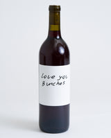 A bottle of Love You Bunches Natural Sangiovese with a plain white label featuring the handwritten message "love you Bunches," set against a simple light background.