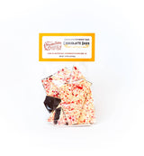 A clear bag of Peppermint Candy Chocolate Bark, featuring white and dark chocolate pieces topped with crushed peppermint, displayed against a plain white background.