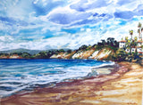 A watercolor print of Haskell's Beach and the Bacara by Karin Shelton captures gentle waves, sandy shore, white houses, palm trees, and distant cliffs—evoking a tranquil Santa Barbara scene.