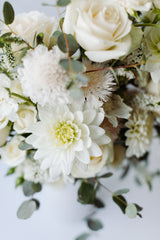 A close-up of the Serene Mama Arrangement: elegant white roses, dahlias, and local farm flowers with green eucalyptus, set against a soft background. Designed by a no foam florist.