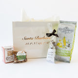 The Sweet & Savory Santa Barbara Welcome Tote features a white tote with gold lettering, filled with cookies, chocolate-covered pretzels, candied almonds, and organic popcorn—ideal for fans of California gourmet treats.