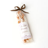 A clear bag tied with a brown ribbon holds sea salt caramels labeled with Jessica Foster Confections branding—an ideal treat in the Sweet & Savory Santa Barbara Welcome Tote, perfect for gifting California gourmet snacks.