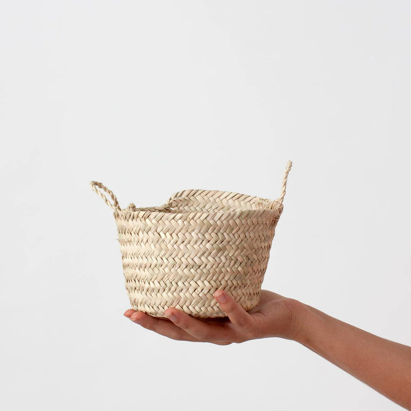 Tiny hand woven basket made from natural palm leaf with two small handles to carry it